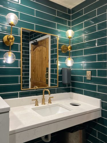 A,Bathroom,With,Green,Subway,Tile,Walls,,Gold,Lights,,Marble